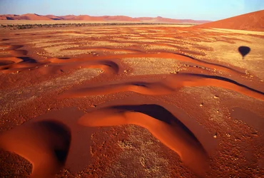 Vue sur une vallée de dunes de sable depuis un vol en montgolfière juste après le lever du soleil près de Sossusvlei dans le désert du Namib, Namibie. 24-07-2003.